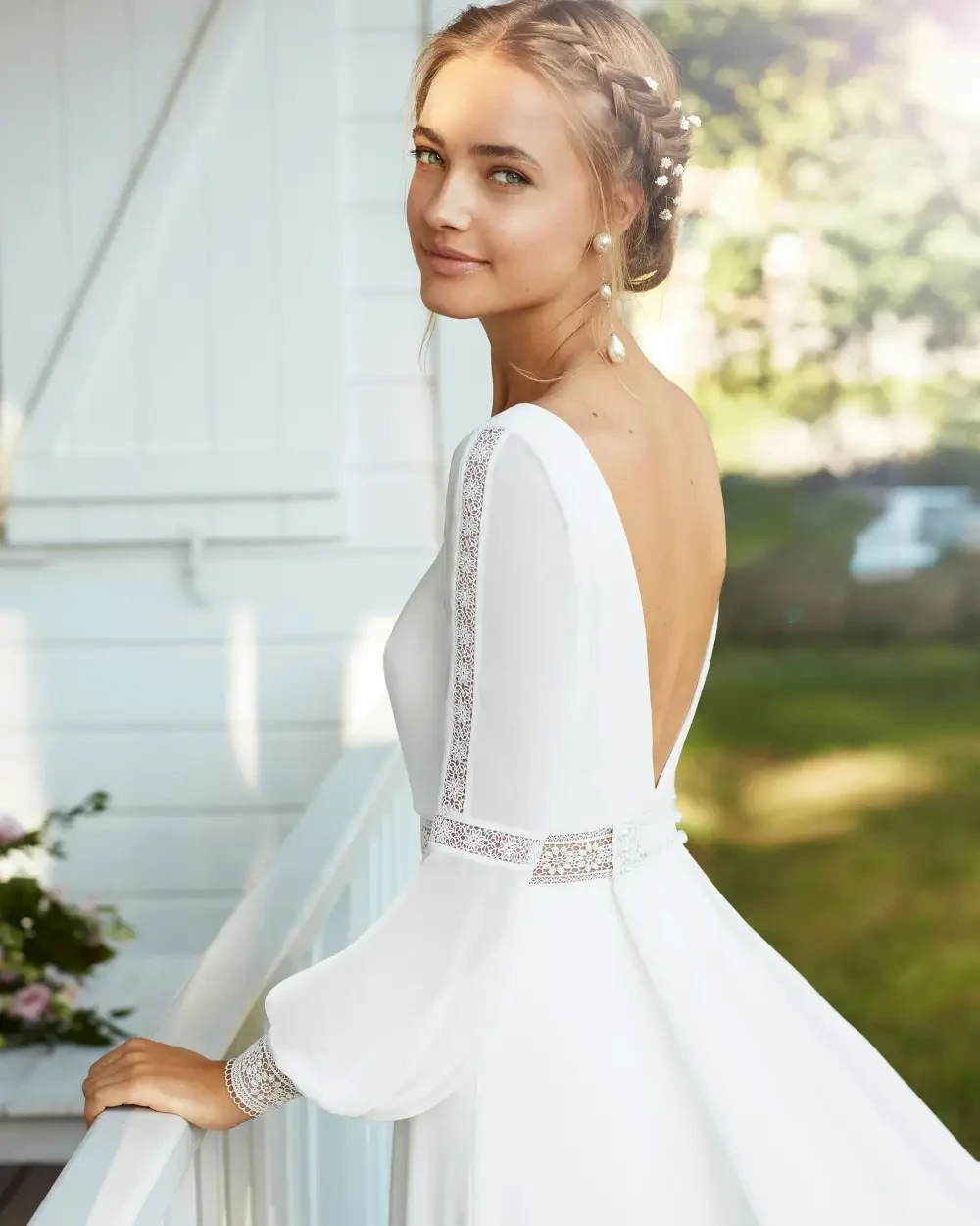 model is wearing an open back long sleeve wedding dress