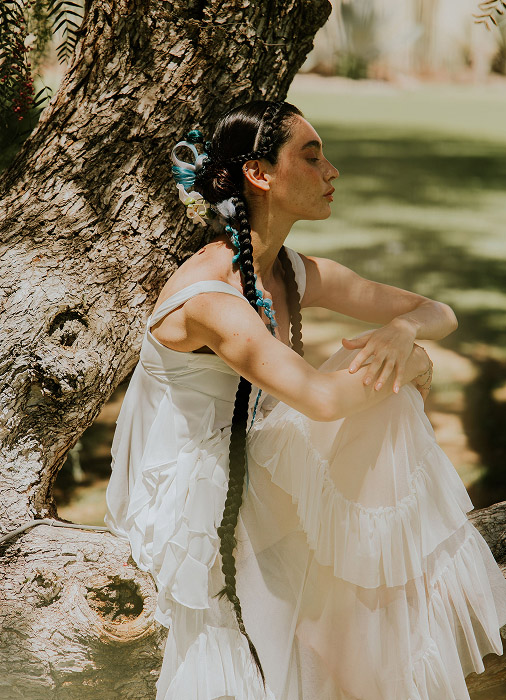 Model wearing a white gown and posing near the tree